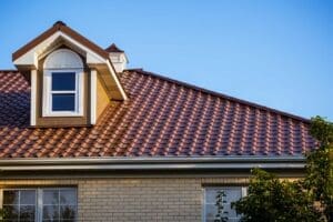 A house with a red tiled roof and a dormer window under a clear blue sky.