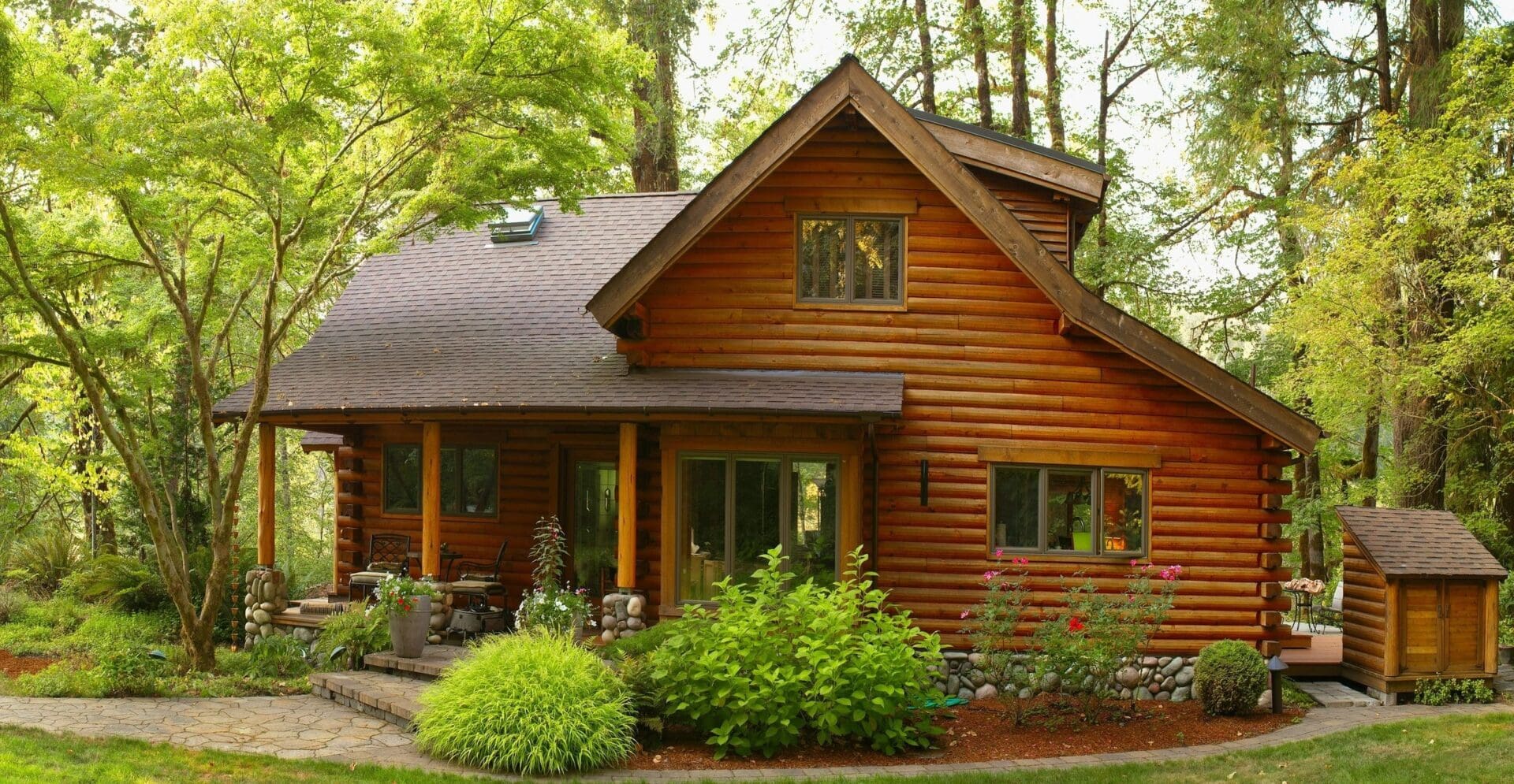 A log cabin with a porch and a large tree.