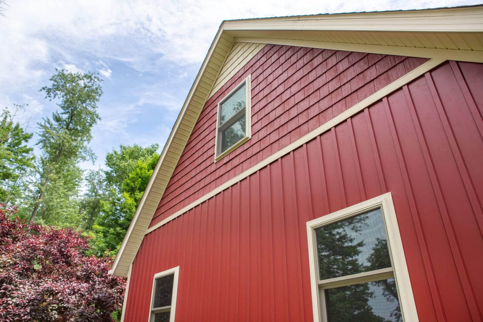 Red barn-style house with white trim under a blue sky.
