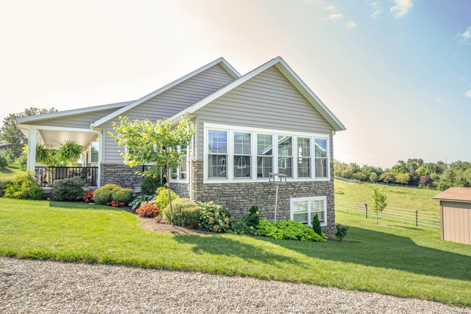 A modern house with large windows and a stone foundation under a clear sky.