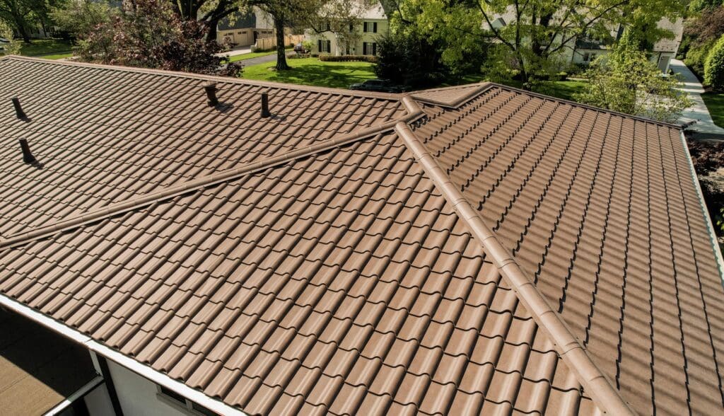 A neatly tiled brown roof on a residential house under a sunny sky.