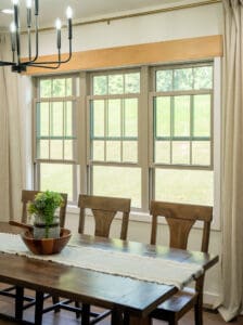 Sunlit dining room with wooden chairs and a potted plant on the table.