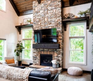 Cozy living room with stone fireplace and large windows.