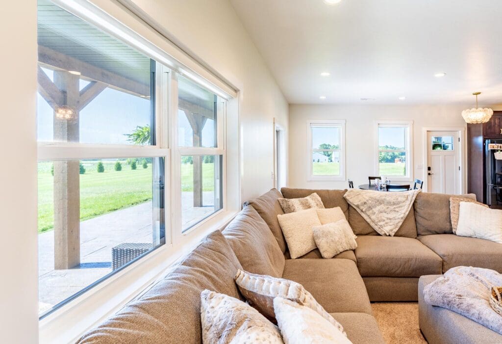 Bright living room with a large beige sectional sofa and sliding glass doors to a green backyard.