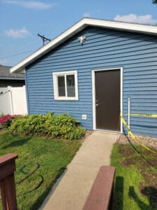 Blue house exterior with a brown door and small garden path.