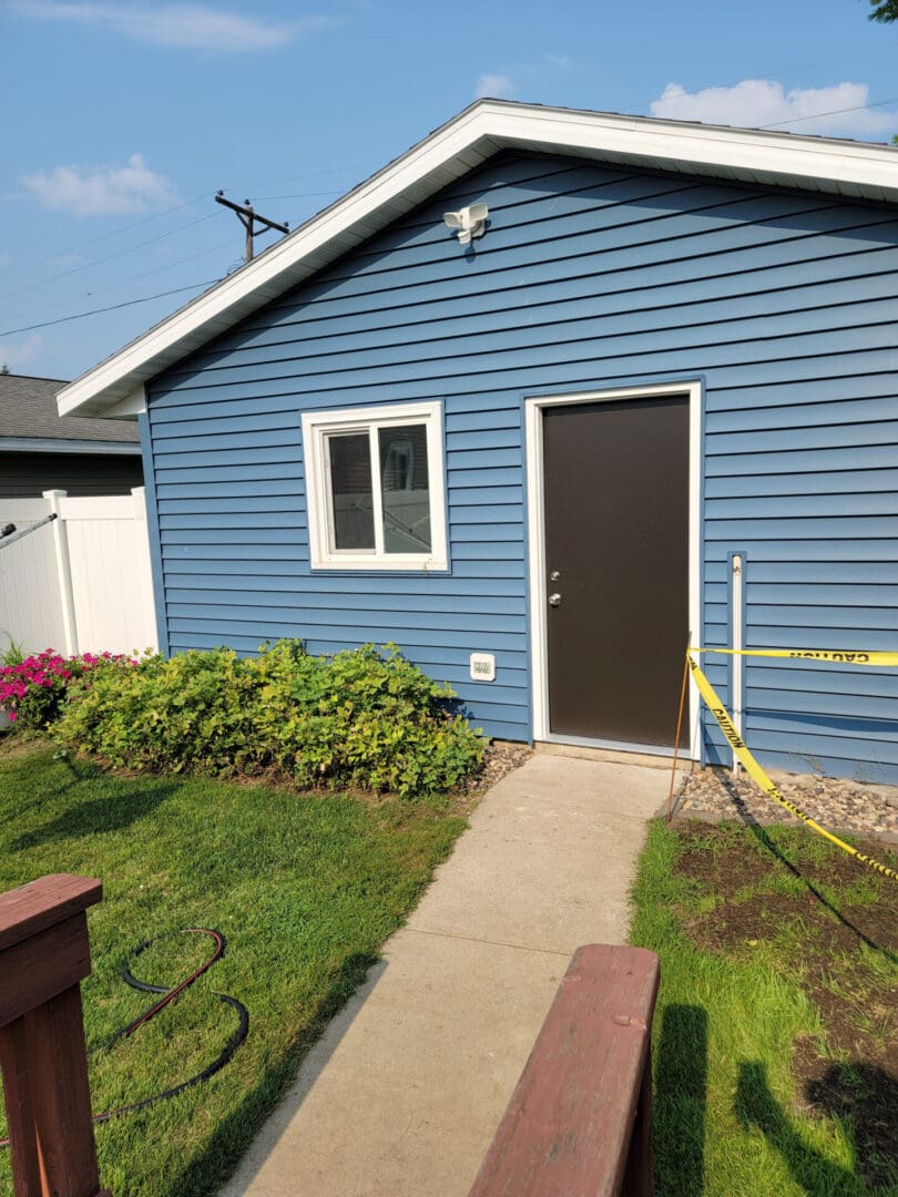 Blue house exterior with a brown door and small garden path.