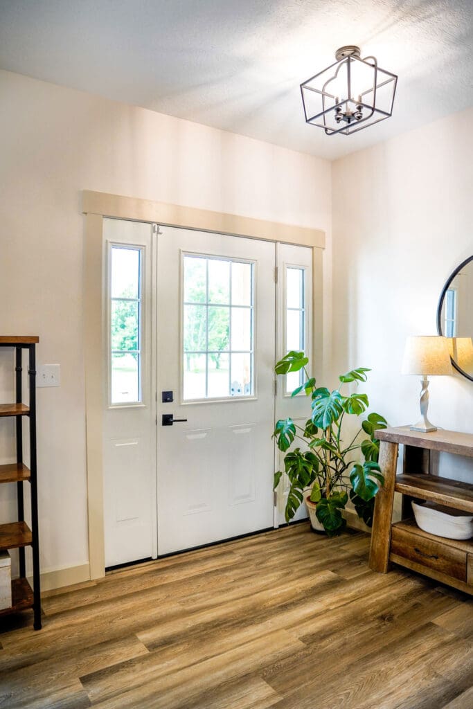 Bright entryway with plants and wooden furniture.