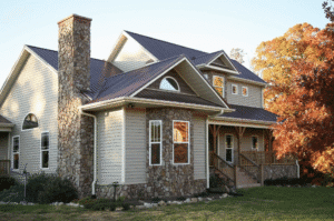 A charming two-story house with stone and siding exterior under a clear sky.