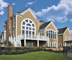 Large two-story house with multiple windows, a chimney, and a clear blue sky in the background.