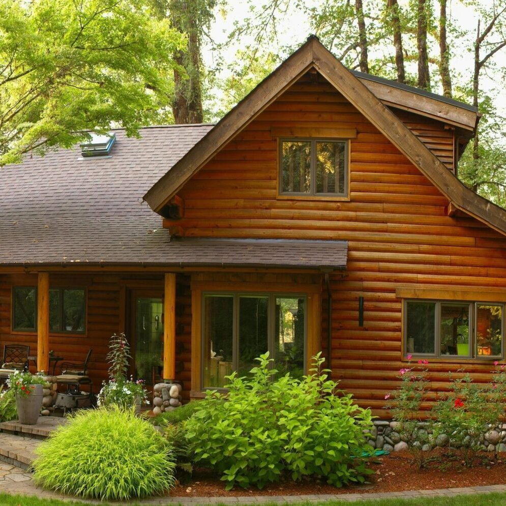 A cozy log cabin surrounded by lush greenery and a manicured garden.