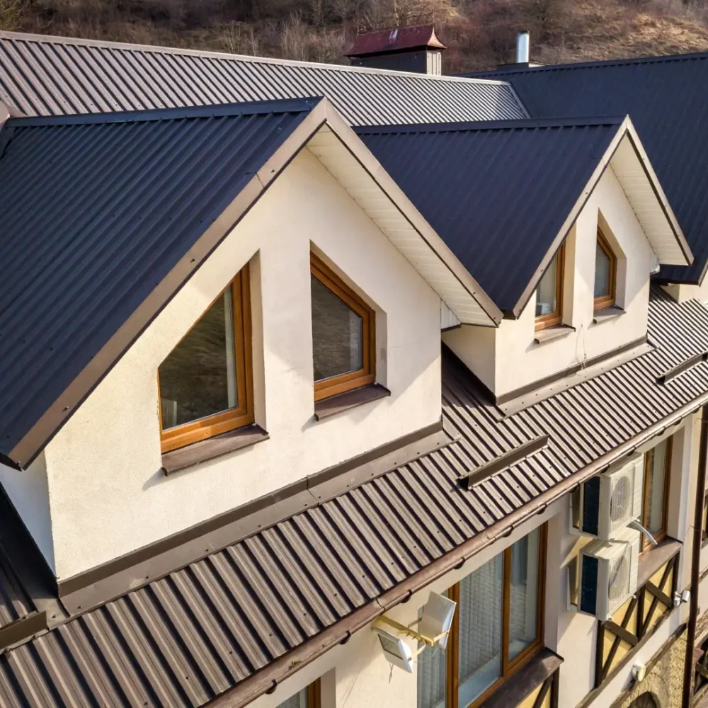 Close-up aerial view of building attic rooms exterior on metal shingle roof.