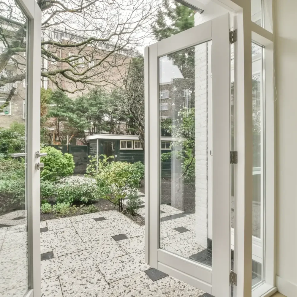 A glass patio door opening to a garden with black and white tiles.