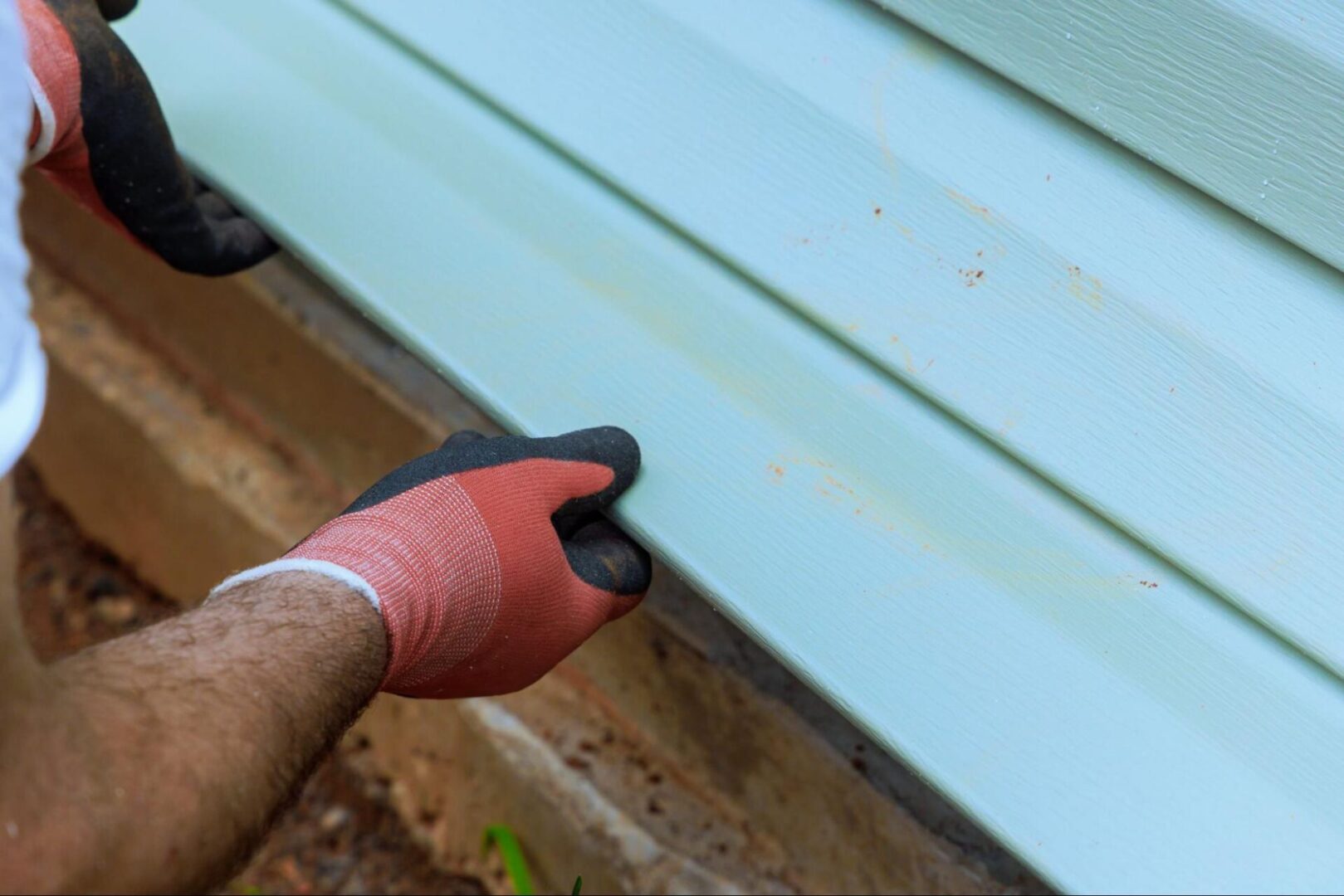 Worker in gloves holding vinyl siding.