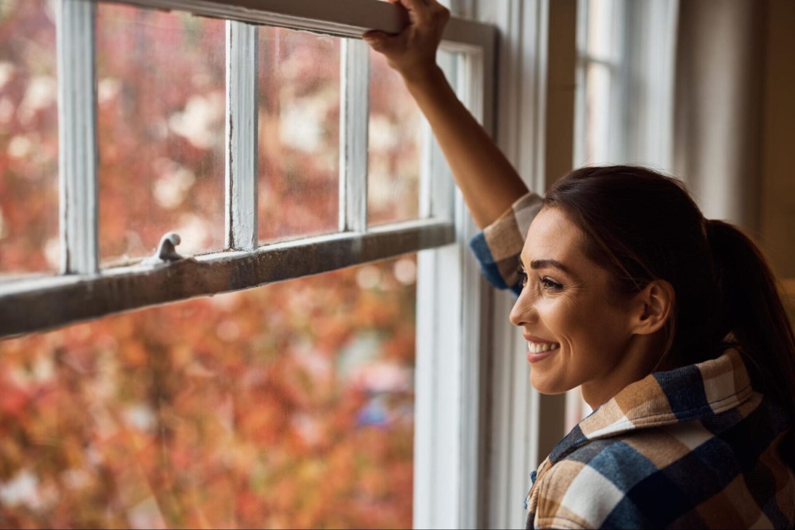 Woman smiling and opening a window. 