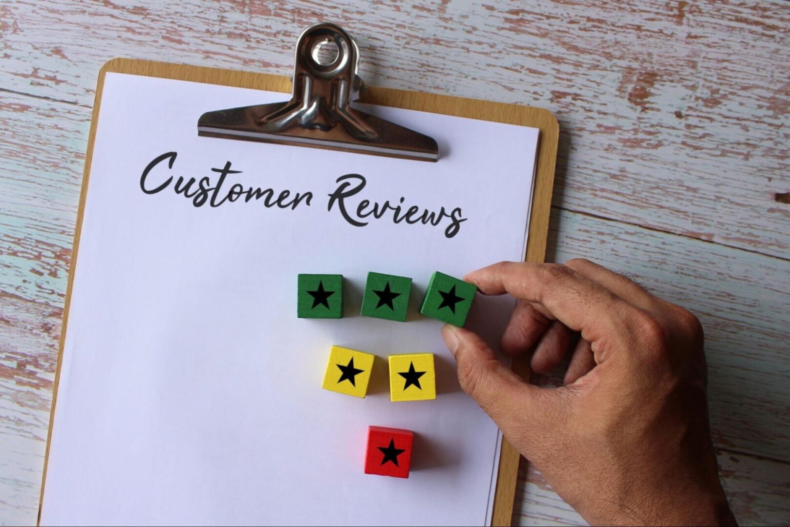 Clipboard with the words “customer reviews” with blocks with stars on them. 