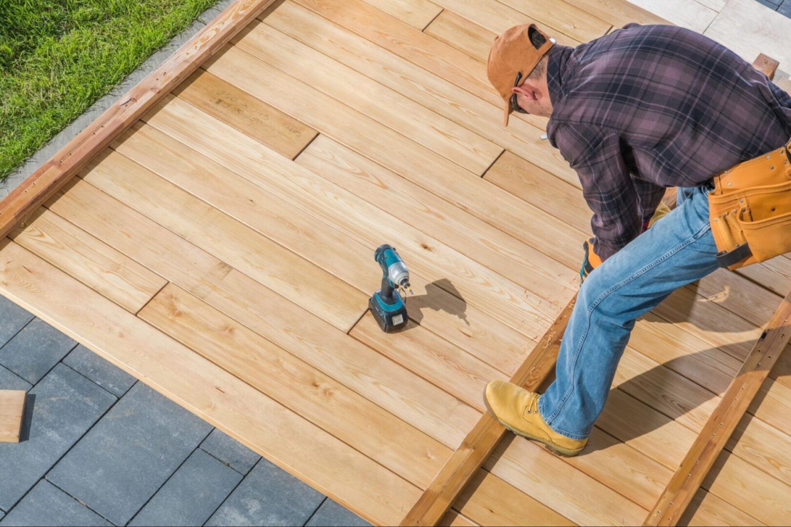 A carpenter installs deck materials in a garden.