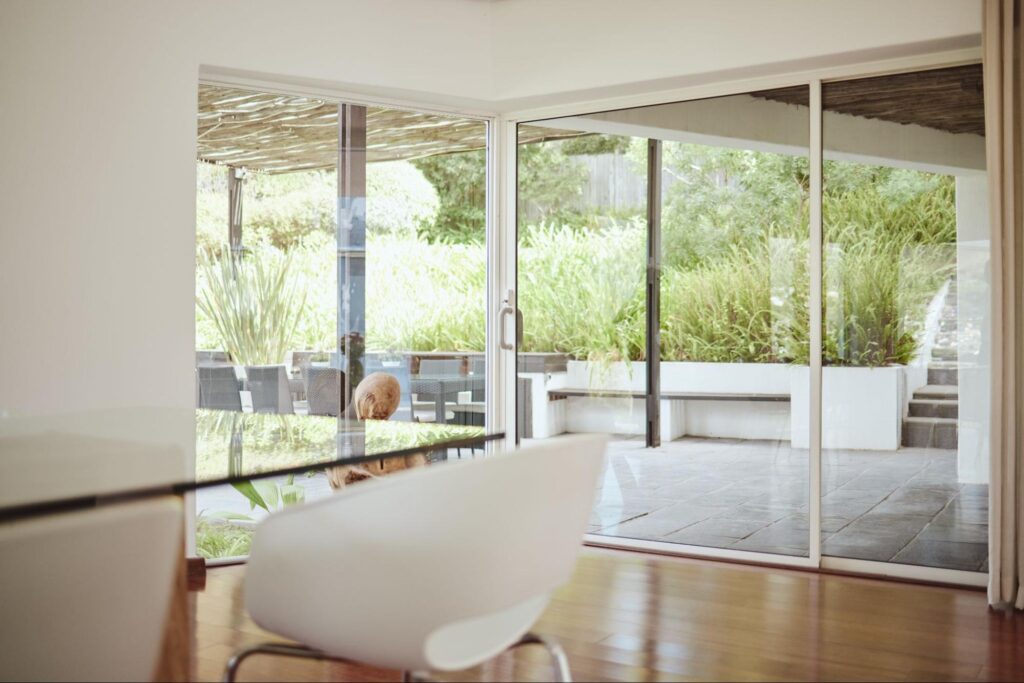 Modern boardroom with sleek furniture and workspace featuring a large table and sliding glass doors in a white frame.