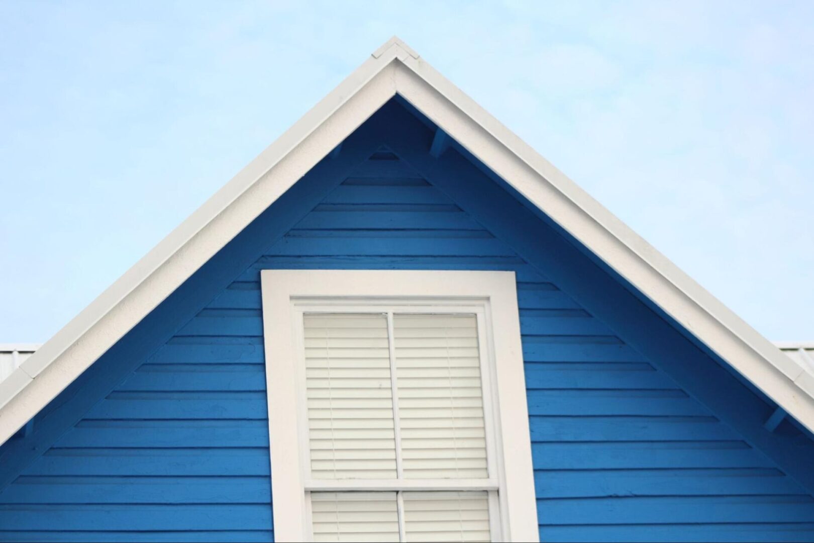 Siding and a window on a home with a view of the sky. 