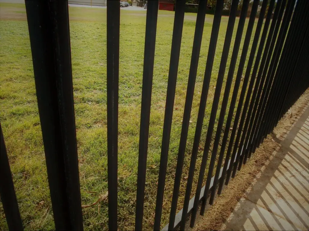 Metal fence with grass in the background.