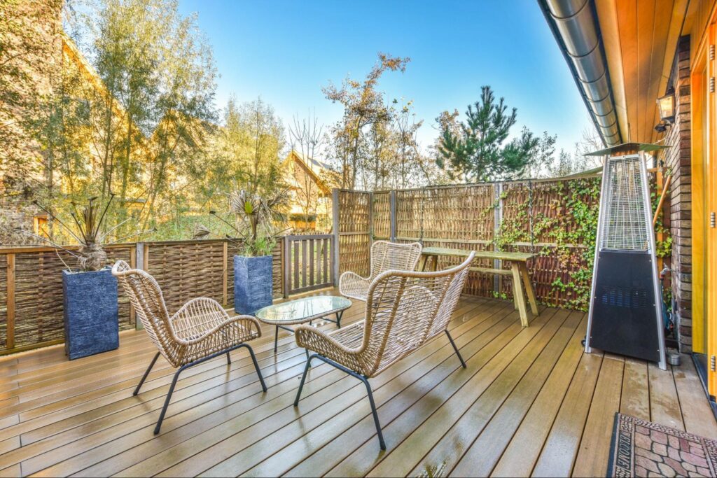 Wooden deck with plants, a heater, and outdoor furniture.