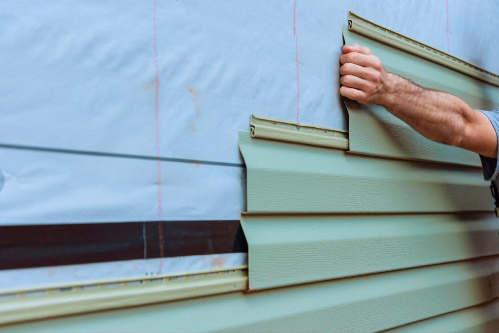 A close-up of vinyl siding panels installed on a house’s exterior wall.