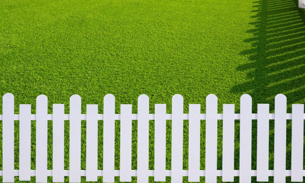 White picket fence in front of a lawn. 