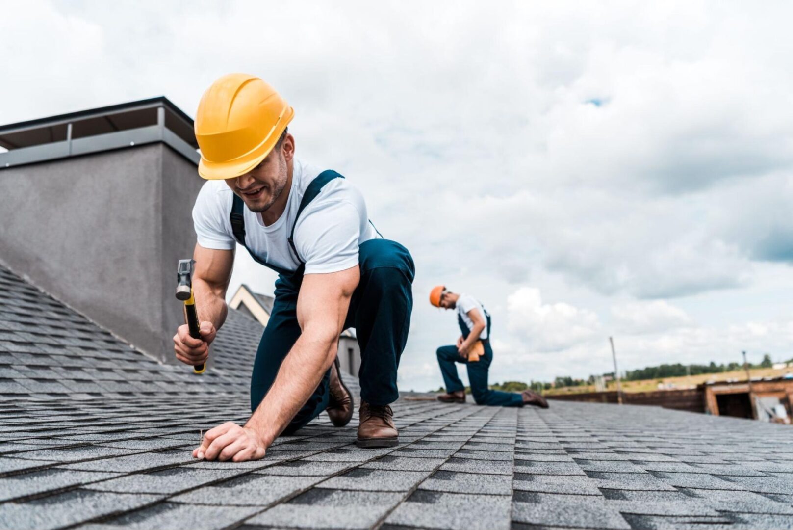 Man in a hard hat using a hammer and a nail. 