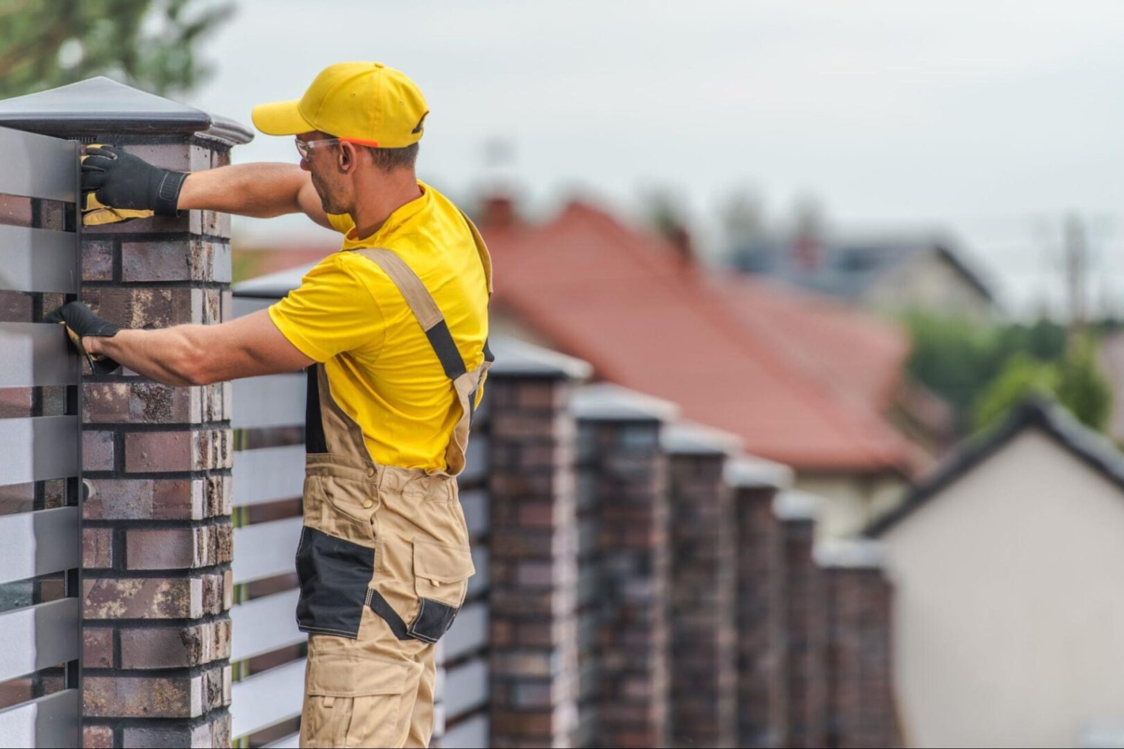 A fence installer fixing the part of a fence attached to a post.