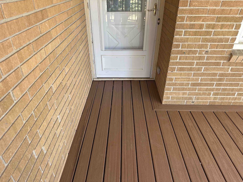 This composite deck features clean, wood-like boards seamlessly integrated with a brick exterior, offering a durable, low-maintenance, and visually appealing entryway. 