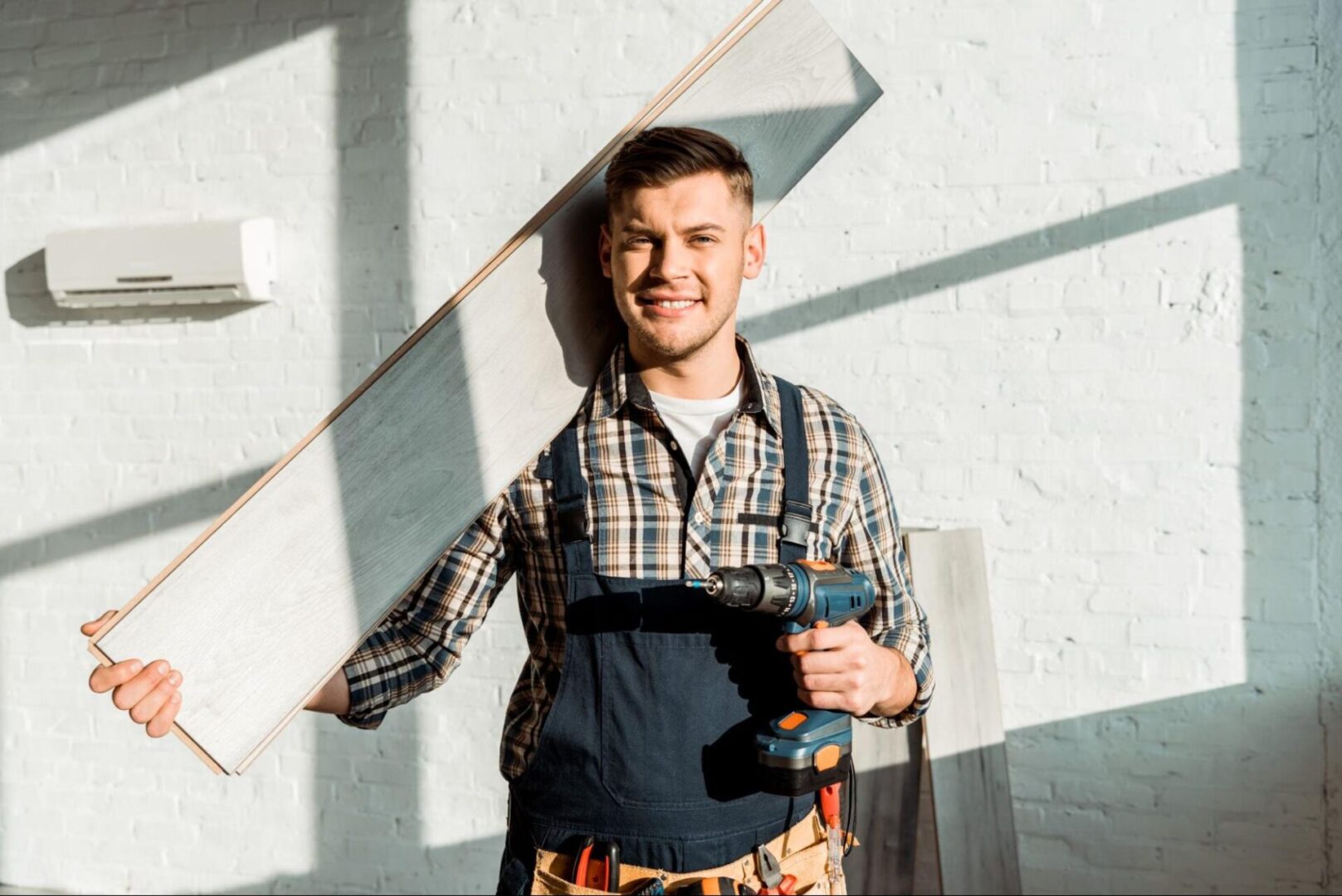 Man holding a power tool and a plank of wood. 