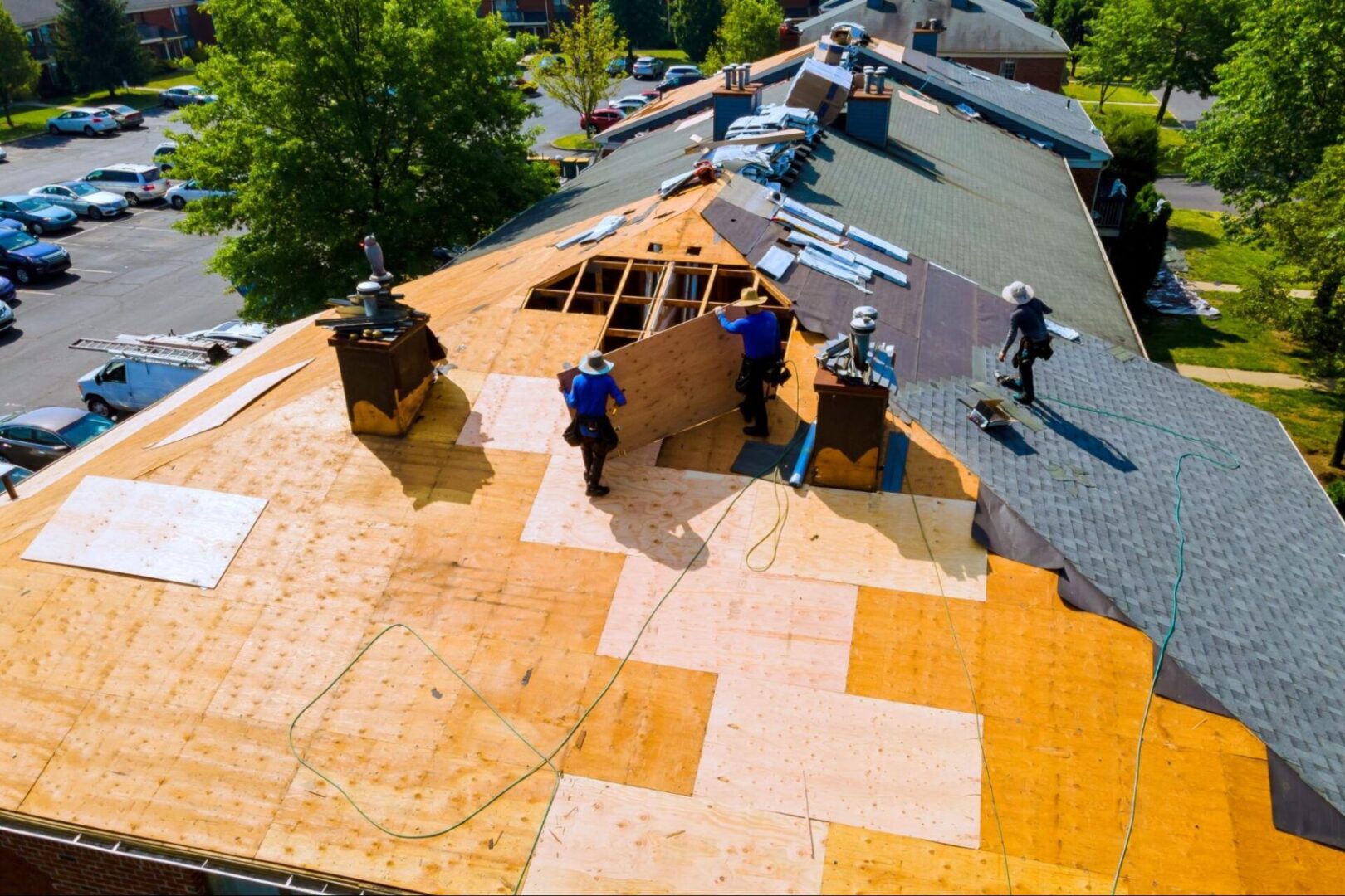 Workers replace worn asphalt shingles on a residential roof.