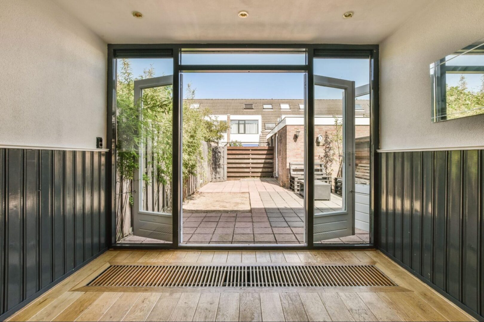 A bright, empty room with white walls, parquet flooring, and a patio door that opens to a scenic outdoor space.