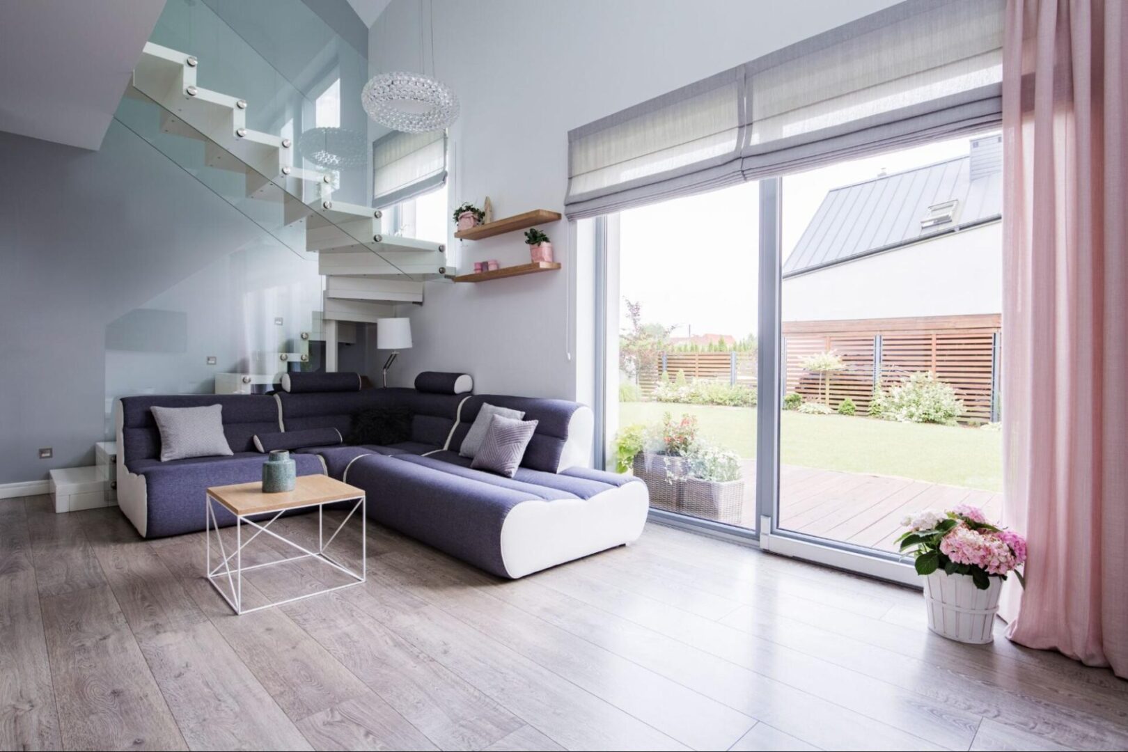 Natural light streams through a large glass door, illuminating a monochromatic living room with modern, minimalist décor.