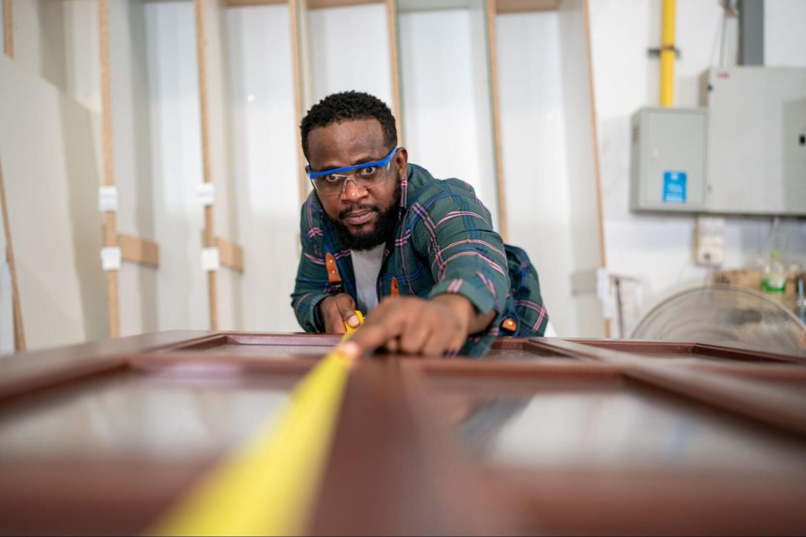 Man in goggles using a measuring tape. 