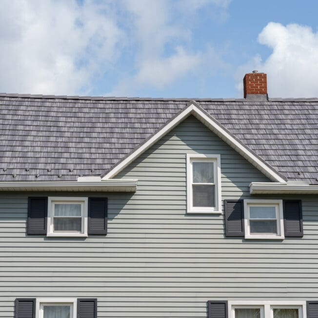 Gray house gable with three windows and chimney